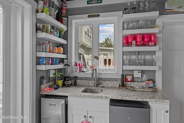 bar with stainless steel dishwasher, indoor wet bar, and a sink