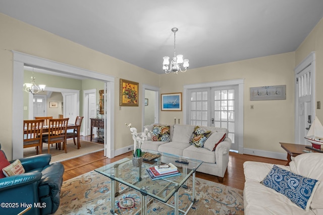 living area with baseboards, an inviting chandelier, and wood finished floors