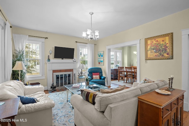 living room featuring light wood finished floors, a fireplace, and an inviting chandelier