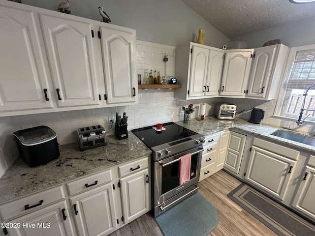 kitchen with stainless steel electric range oven, light wood-style flooring, white cabinets, a sink, and a textured ceiling