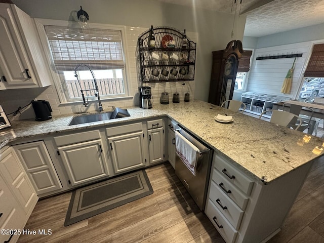 kitchen featuring a peninsula, light wood-type flooring, a sink, and decorative backsplash