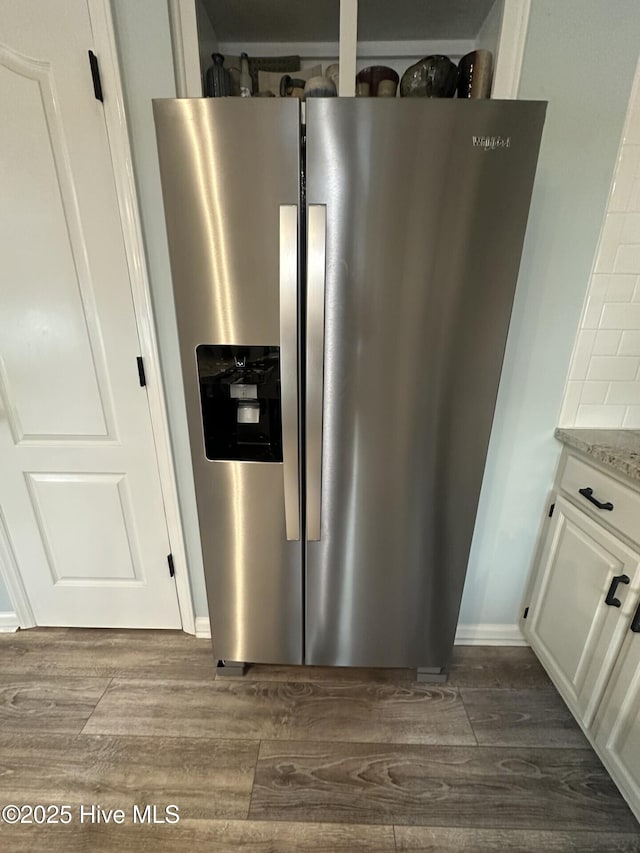 details with stainless steel refrigerator with ice dispenser, dark wood finished floors, white cabinetry, and light stone countertops