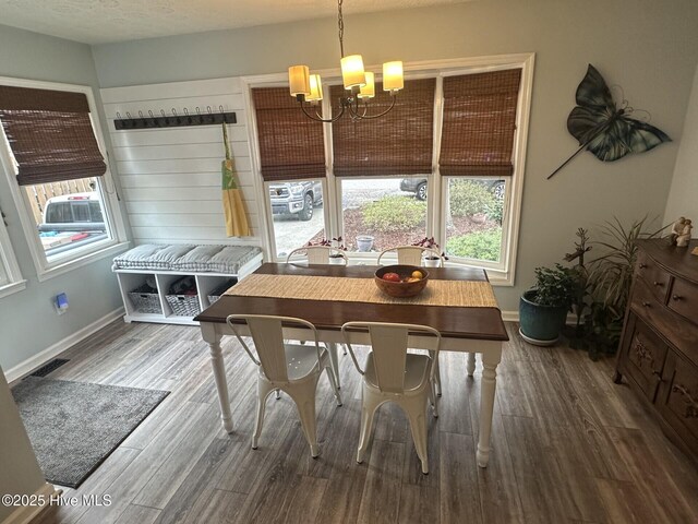 dining space with baseboards, visible vents, wood finished floors, a textured ceiling, and a notable chandelier