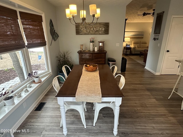 dining space featuring a chandelier, visible vents, baseboards, and wood finished floors