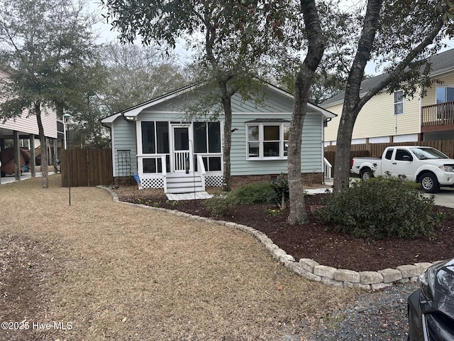 view of front facade featuring a sunroom and fence