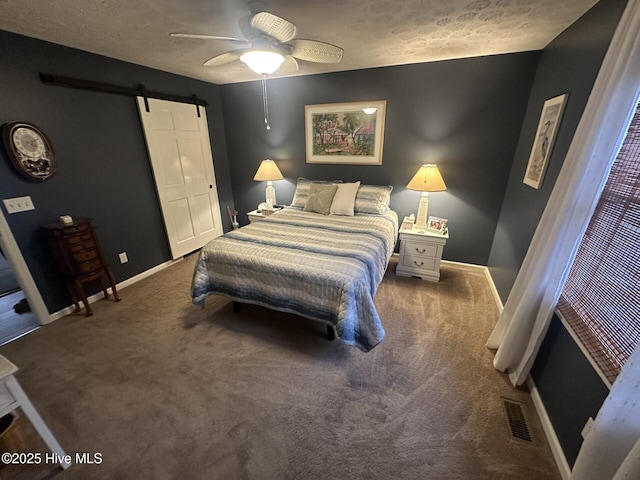 bedroom with a barn door, a ceiling fan, visible vents, baseboards, and carpet