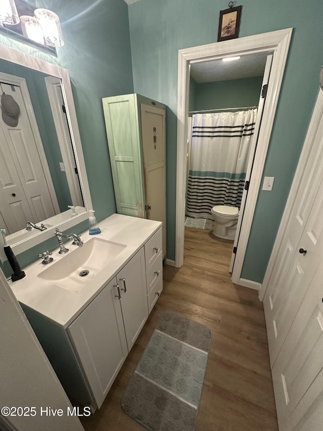 full bath with toilet, wood finished floors, and vanity