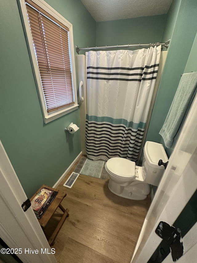 full bath featuring toilet, wood finished floors, visible vents, baseboards, and a shower with curtain