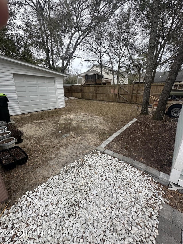 view of yard featuring an outbuilding, a garage, fence, driveway, and a gate