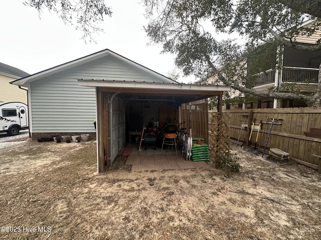 garage featuring fence and a detached carport