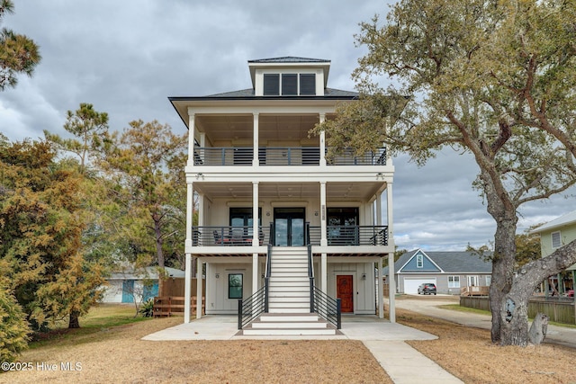 raised beach house featuring stairs, a balcony, and board and batten siding