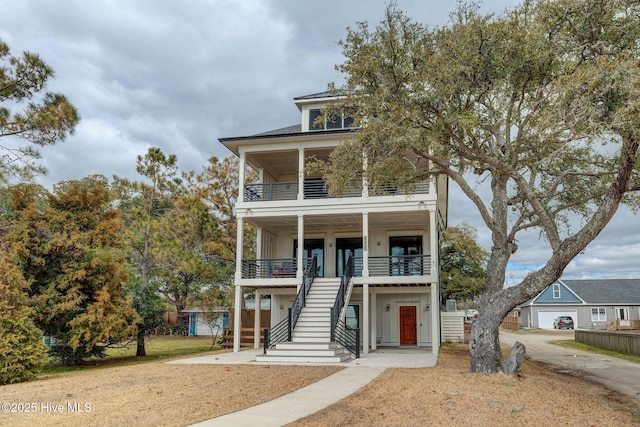 beach home featuring a balcony, board and batten siding, and stairs