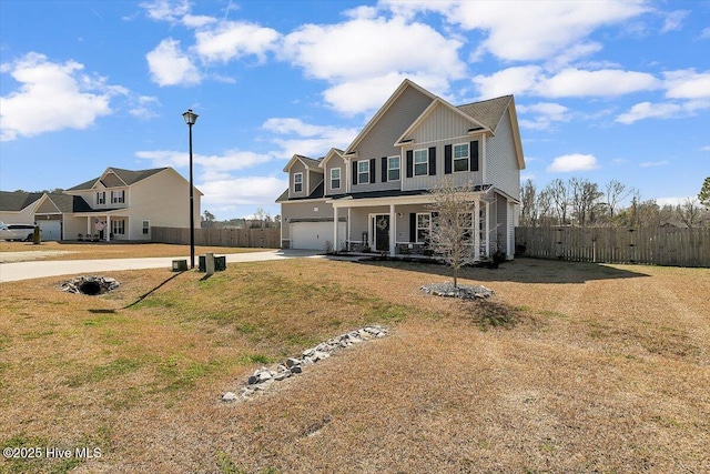 traditional home with an attached garage, covered porch, driveway, and fence