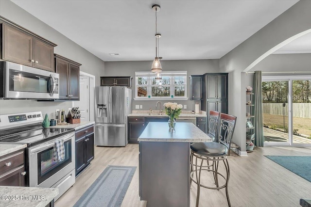 kitchen with a breakfast bar, light wood-style flooring, a sink, stainless steel appliances, and light countertops