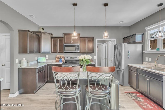 kitchen with visible vents, a kitchen island, arched walkways, stainless steel appliances, and a sink