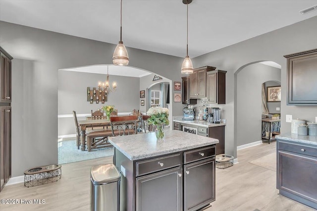 kitchen with light wood finished floors, visible vents, arched walkways, and light countertops