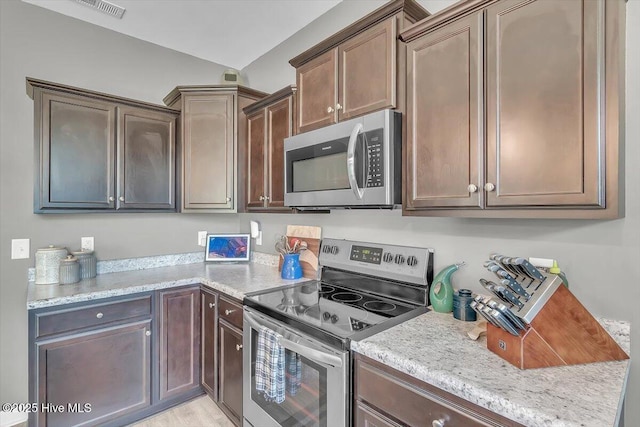 kitchen featuring light stone counters, stainless steel appliances, and visible vents