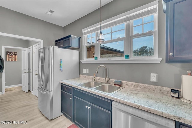 kitchen with visible vents, blue cabinetry, a sink, appliances with stainless steel finishes, and light wood-type flooring