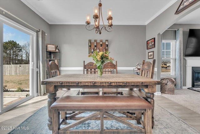 carpeted dining area featuring a notable chandelier, a glass covered fireplace, arched walkways, and ornamental molding