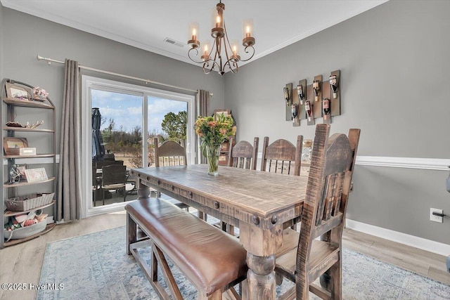 dining room featuring baseboards, visible vents, an inviting chandelier, ornamental molding, and light wood-type flooring