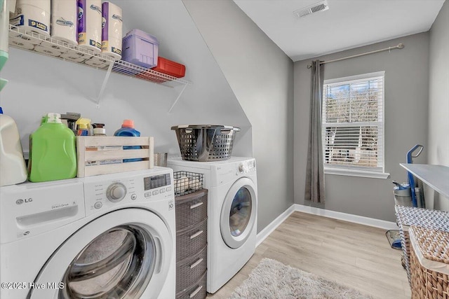 washroom featuring light wood-type flooring, visible vents, baseboards, laundry area, and washing machine and clothes dryer