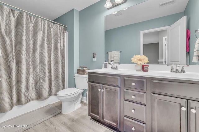 full bath with double vanity, visible vents, toilet, and a sink