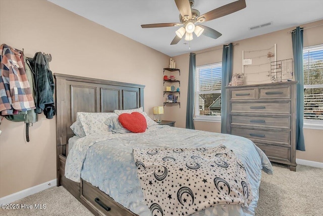 carpeted bedroom featuring visible vents, multiple windows, a ceiling fan, and baseboards