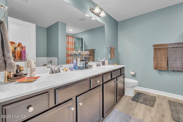 full bath with a sink, toilet, wood finished floors, and double vanity