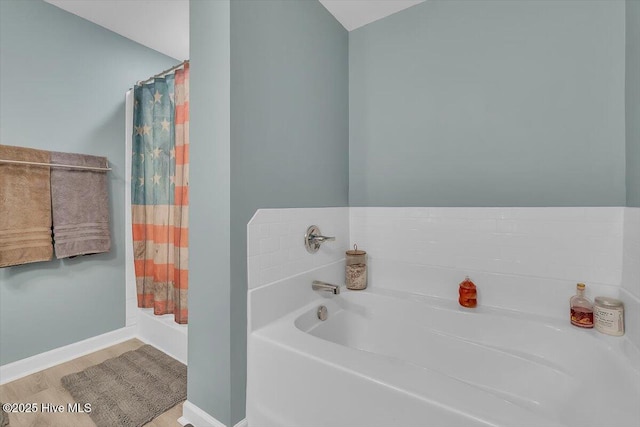 bathroom with a shower with shower curtain, baseboards, and a bath