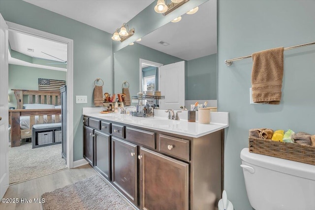 full bathroom with visible vents, toilet, ensuite bathroom, a sink, and double vanity