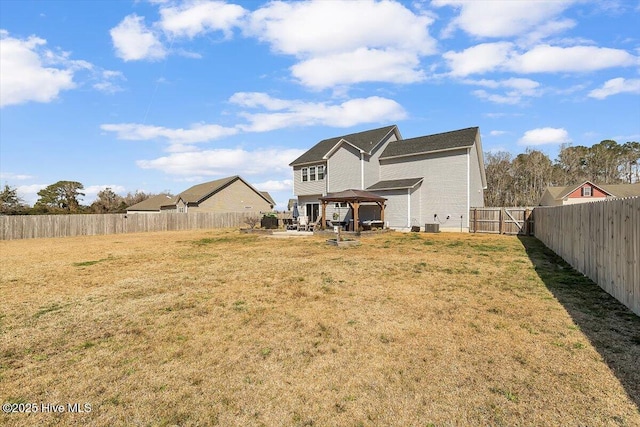 rear view of house featuring a gazebo, a lawn, and a fenced backyard