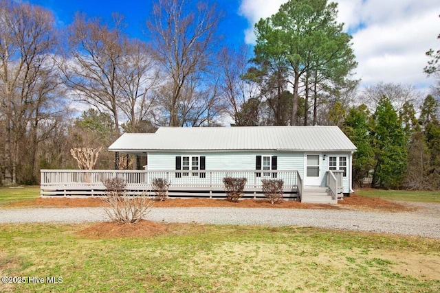 rear view of property with metal roof, a lawn, and a deck