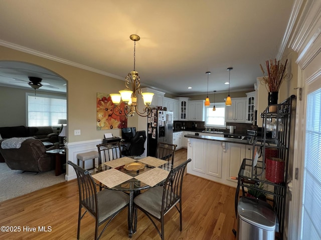 6725 Hemlock Ct, Sims, NC 27880 - dining space with crown molding, ceiling fan with notable chandelier, wainscoting, light wood-style floors, and arched walkways