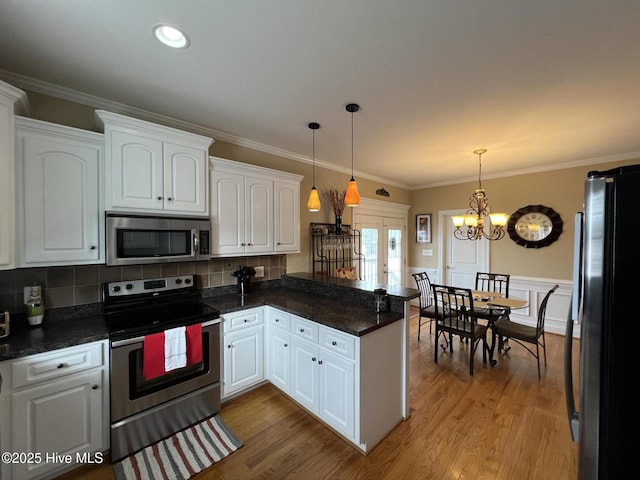 6725 Hemlock Ct, Sims, NC 27880 - kitchen with pendant lighting, appliances with stainless steel finishes, white cabinets, a peninsula, and a notable chandelier