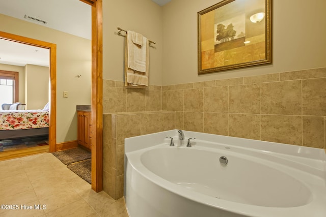 ensuite bathroom featuring tile patterned flooring, visible vents, tile walls, a garden tub, and ensuite bath