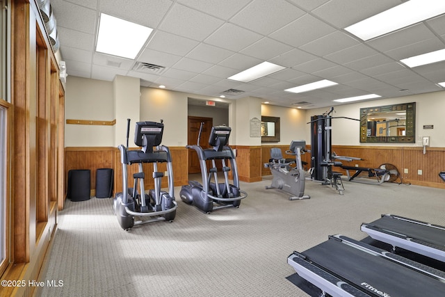 workout area with visible vents, a paneled ceiling, wooden walls, and wainscoting