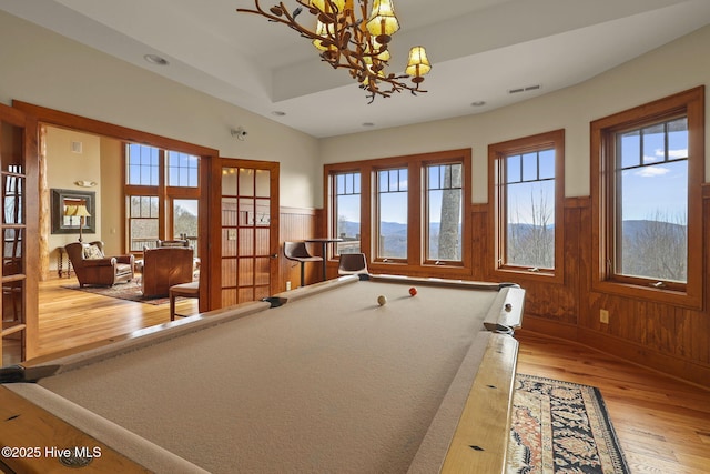 recreation room with visible vents, wood walls, wainscoting, an inviting chandelier, and wood finished floors