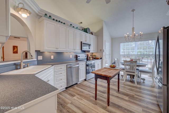 kitchen featuring vaulted ceiling, appliances with stainless steel finishes, white cabinetry, and a sink