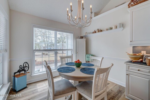 kitchen with light wood finished floors, lofted ceiling, an inviting chandelier, white cabinets, and stainless steel appliances