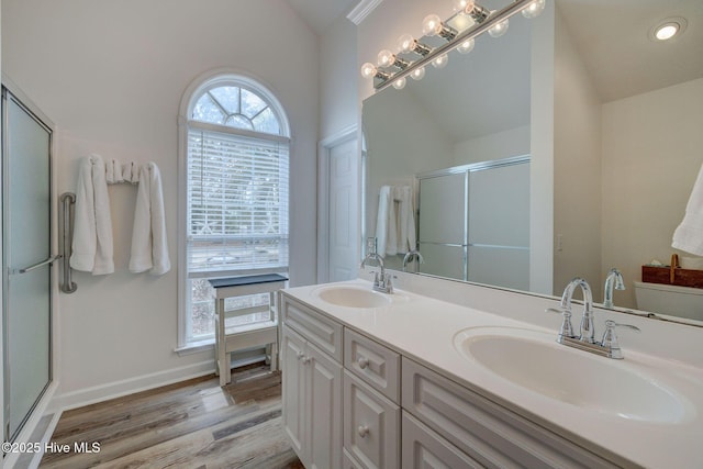 full bathroom featuring vaulted ceiling, wood finished floors, a shower with door, and a sink