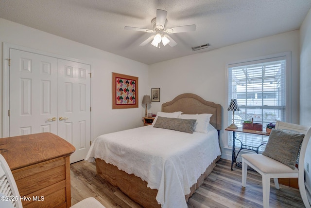 bedroom featuring a closet, visible vents, a textured ceiling, and light wood-style floors