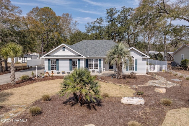 single story home featuring roof with shingles, concrete driveway, and fence