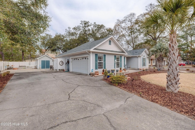 view of front facade featuring fence, a garage, driveway, and a shingled roof