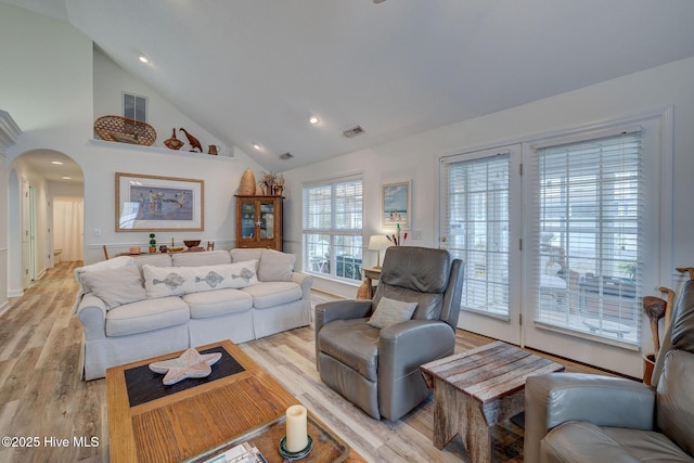 living area featuring visible vents, arched walkways, and light wood finished floors