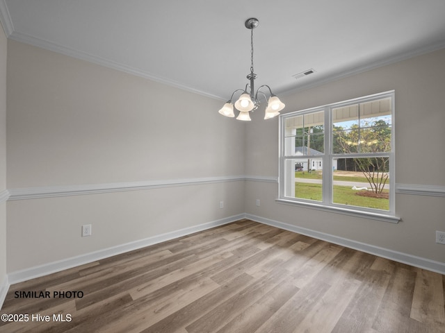 spare room featuring baseboards, an inviting chandelier, wood finished floors, and crown molding