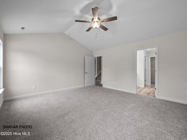 unfurnished bedroom with vaulted ceiling, light colored carpet, visible vents, and baseboards