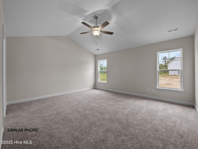 carpeted spare room with lofted ceiling, baseboards, visible vents, and ceiling fan