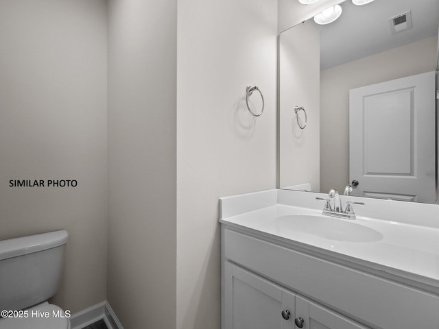 bathroom with vanity, toilet, baseboards, and visible vents