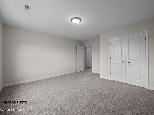 unfurnished bedroom with a closet, visible vents, baseboards, and carpet