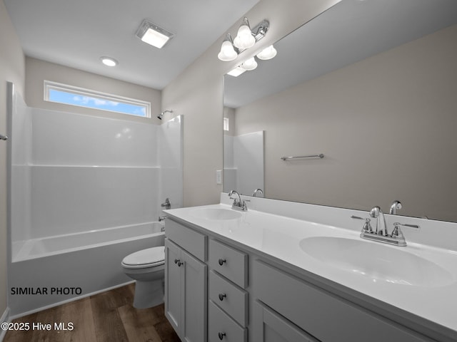 bathroom featuring double vanity, toilet, wood finished floors, and a sink